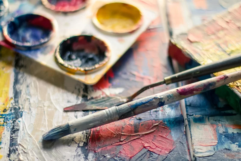 a imagem mostra uma paleta de tintas a óleo e pincéis manchados de tinta