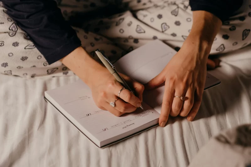 a imagem mostra uma pessoa escrevendo afirmações positivas para si em seu journal na rotina