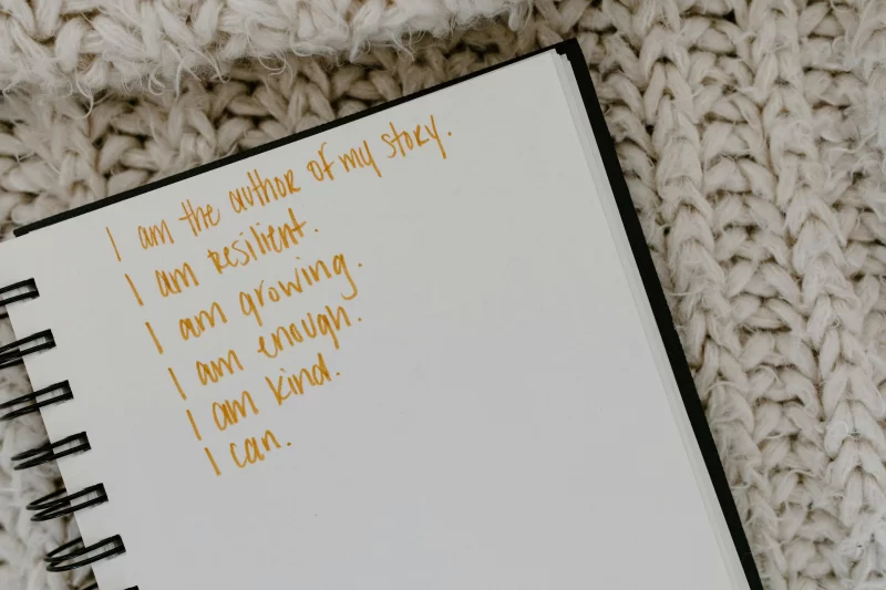 a imagem mostra um caderno com afirmações diárias positivas escritas