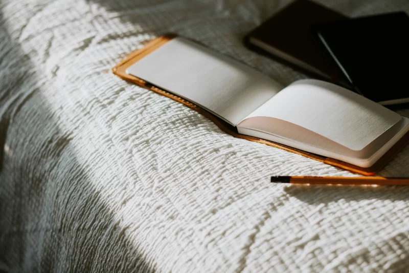 a imagem mostra um caderno de journaling aberto sobre a cama